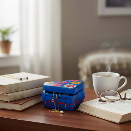 The Talavera Hub heart-shaped blue ceramic jewelry box with hand-painted floral patterns on a wooden desk.