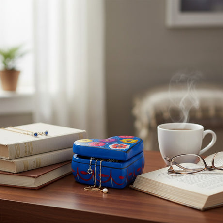 The Talavera Hub heart-shaped blue ceramic jewelry box with hand-painted floral patterns on a wooden desk.
