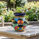 The Talavera Hub hand-painted Mexican ceramic strawberry planter with vibrant floral patterns on a wooden table.