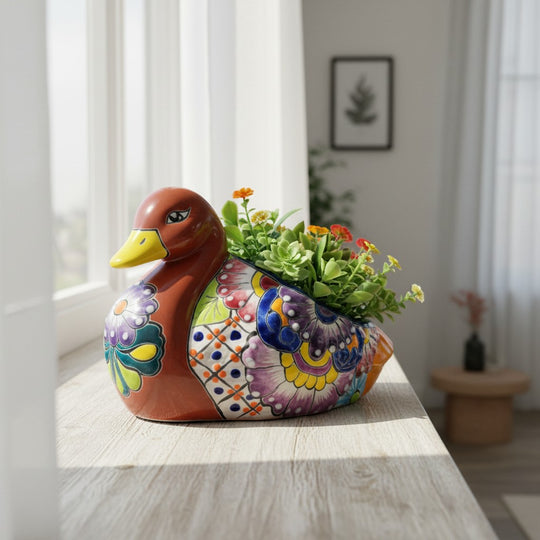 The Talavera Hub handmade Mexican ceramic duck planter with vibrant floral folk art patterns holding small succulents.