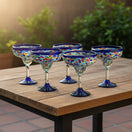 The Talavera Hub Mexican hand-blown margarita glasses with blue confetti rock design and cobalt blue rims.