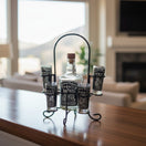 The Talavera Hub Mexican Tequila Decanter Set with 6 shot glasses in a black metal holder. Features rustic Mexican motifs.