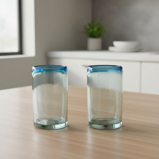 The Talavera Hub Hand-Blown Mexican Tumbler Glass with clear body and teal rim. 5" tall, made from recycled glass.