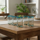 The Talavera Hub hand-blown Mexican tumbler glasses with clear bodies and teal rims, 5" tall, sold as a set.