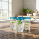 The Talavera Hub hand-blown Mexican tumbler glasses with clear bodies and striking teal rims. Set of 4, 5" tall.