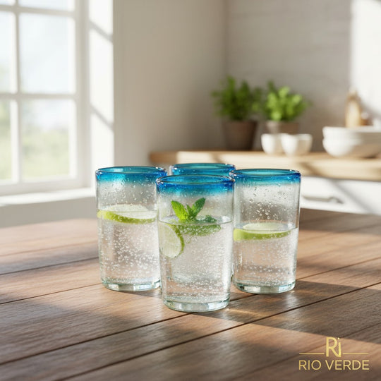 The Talavera Hub hand-blown Mexican tumbler glasses with clear bodies and striking teal rims. Set of 4, 5" tall.