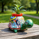 The Talavera Hub medium hand-painted ceramic turtle planter with vibrant floral designs and a red rim.