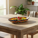 The Talavera Hub oval ceramic serving platter with cobalt-blue rim and vibrant hand-painted floral motifs on wood table