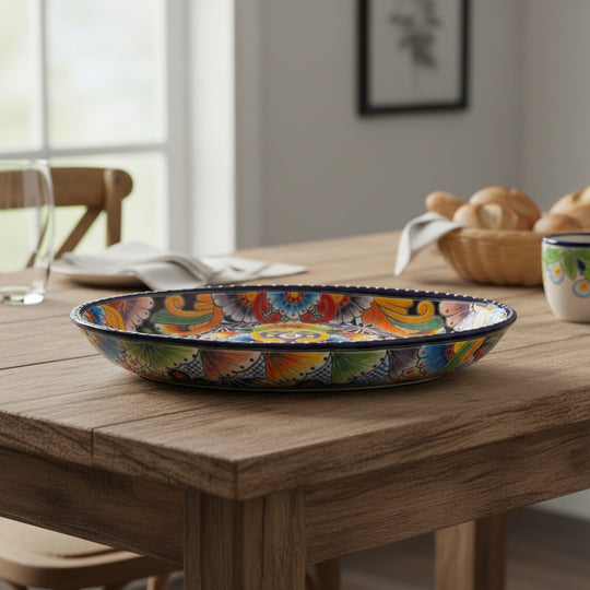 The Talavera Hub oval ceramic serving platter with vibrant hand-painted floral motifs and a cobalt blue rim on a table.