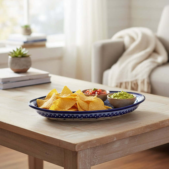 The Talavera Hub oval serving platter with blue and white hand-painted patterns holding tortilla chips and dips.