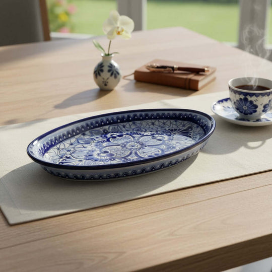 The Talavera Hub oval serving platter with hand-painted blue and white floral patterns on a wooden dining table.