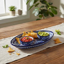 The Talavera Hub oval serving platter with blue and white hand-painted Mexican patterns holding salsa and guacamole.