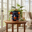 The Talavera Hub hand-painted ceramic pig planter with colorful floral and geometric patterns. Features orange ears and feet, blue eyes.