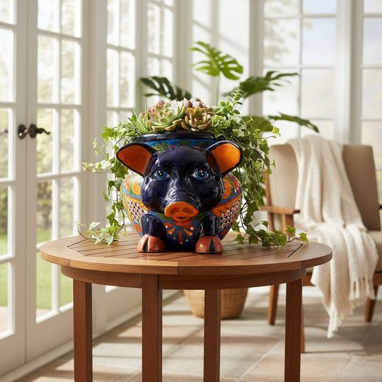 The Talavera Hub hand-painted ceramic pig planter with colorful floral and geometric patterns. Features orange ears and feet, blue eyes.