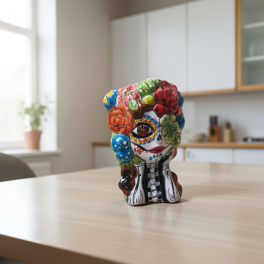 The Talavera Hub hand-painted ceramic Day of the Dead skull planter with floral motifs in red, green, blue, and yellow. 9.5" tall.