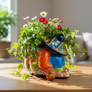 The Talavera Hub colorful ceramic planter shaped like a sleeping man in a sombrero, hand-painted with orange, blue, green, and red.