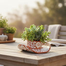 The Talavera Hub handcrafted brown and white floral sombrero planter filled with assorted succulents on a wooden table