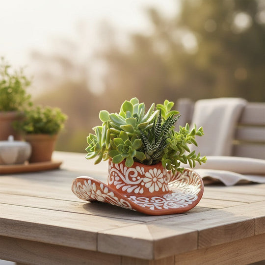 The Talavera Hub handcrafted brown and white floral sombrero planter filled with assorted succulents on a wooden table