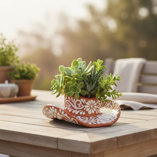 The Talavera Hub handcrafted brown and white floral sombrero planter filled with assorted succulents on a wooden table