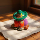 The Talavera Hub handmade Talavera Panchito figurine featuring a sleeping man in a vibrant green sombrero and colorful clothes.