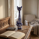 The Talavera Hub tall blue and white ceramic cat statue with intricate hand-painted floral patterns on a wooden desk.