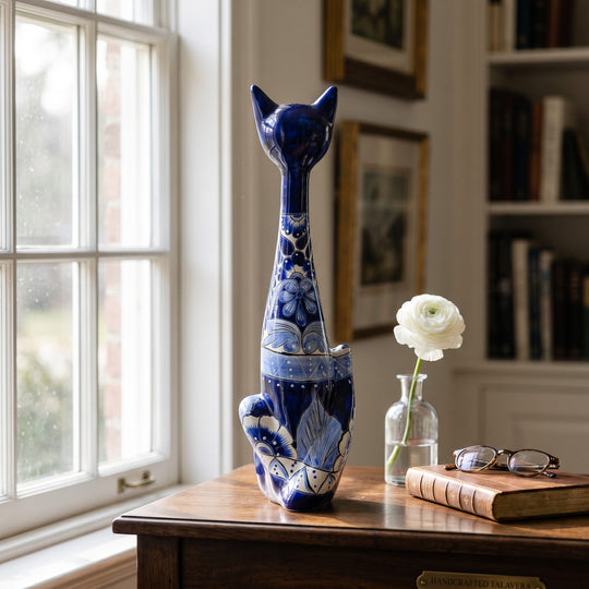 The Talavera Hub tall blue and white ceramic cat statue with intricate hand-painted floral patterns on a wooden desk.