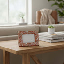 The Talavera Hub handmade terracotta photo frame with white floral patterns displayed on a wooden console table.