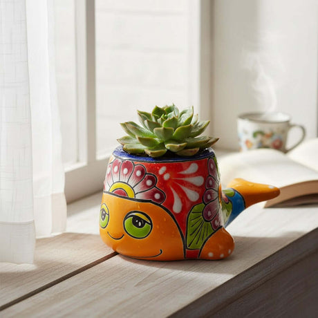 The Talavera Hub small whale planter with vibrant hand-painted floral patterns in orange, red, and blue on a windowsill