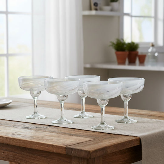 The Talavera Hub two hand-blown clear margarita glasses with white swirl patterns and thick stems.