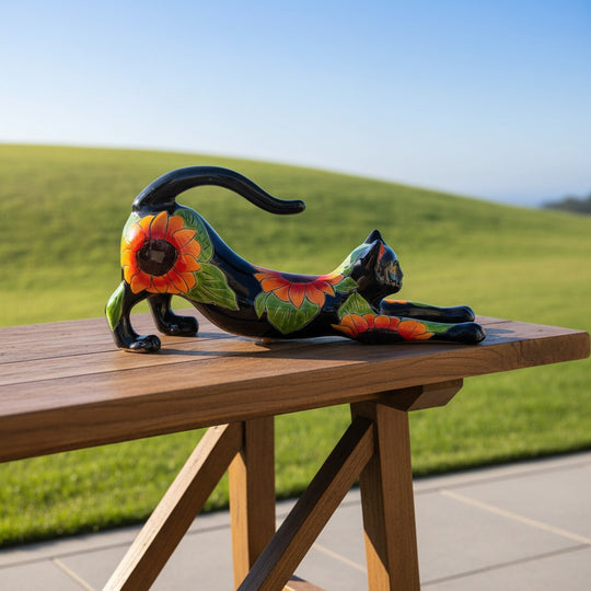 The Talavera Hub black ceramic cat statue with hand-painted sunflower design, stretching pose.