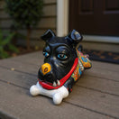 The Talavera Hub handpainted black ceramic dog decor with blue eyes, yellow nose, red collar, and bone in mouth.