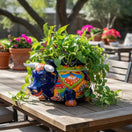 The Talavera Hub blue ceramic bull planter with vibrant floral patterns in orange, green, and red. Hand-painted Mexican pottery.