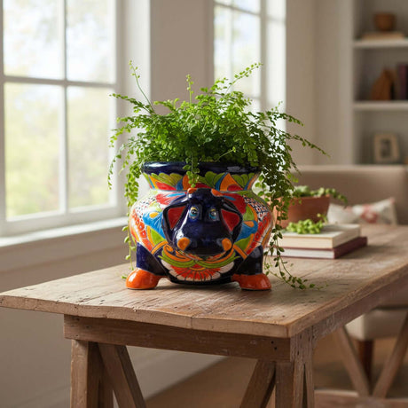 The Talavera Hub handcrafted blue ceramic cow planter with vibrant floral patterns and orange hooves.