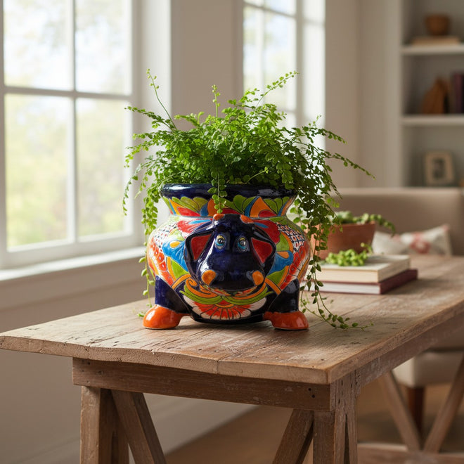 The Talavera Hub handcrafted blue ceramic cow planter with vibrant floral patterns and orange hooves.