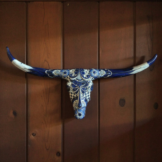The Talavera Hub blue and white ceramic longhorn skull wall art with intricate floral and geometric patterns.