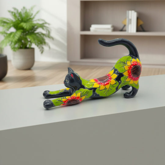 The Talavera Hub hand-painted ceramic cat statue with sunflower design, stretching pose, black with yellow and red flowers.
