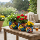 The Talavera Hub set of 3 colorful hand-painted ceramic flower pots with floral designs and blue rims.
