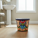 The Talavera Hub handmade ceramic oval trash can with vibrant floral and geometric Talavera designs in blue, orange, red, green, and white.