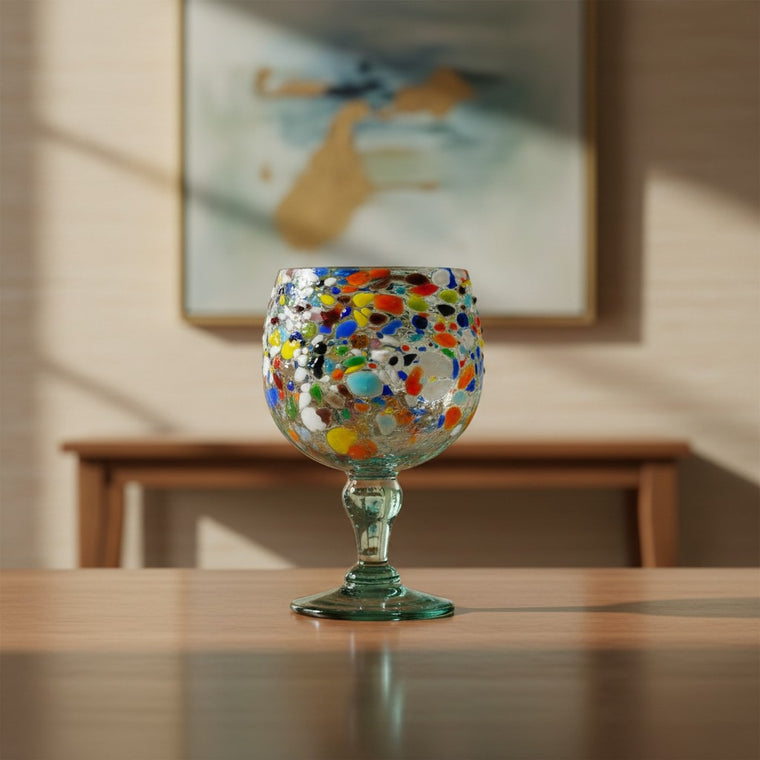 The Talavera Hub oversized fish bowl margarita glass with colorful confetti pebble design. Hand-blown recycled glass, 23 oz.