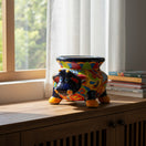 The Talavera Hub handcrafted dark blue cow planter with vibrant floral and geometric patterns, orange hooves, and blue eyes.