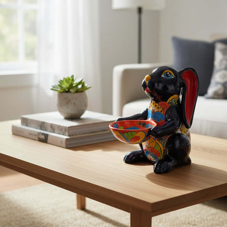 The Talavera Hub dark blue ceramic bunny statue with red ears, holding a colorful Talavera bowl. Handcrafted Mexican folk art.