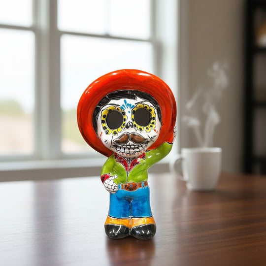 The Talavera Hub hand-painted ceramic skeleton man figurine with red sombrero, Day of the Dead decor.