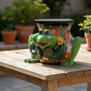 The Talavera Hub green ceramic frog planter with colorful hand-painted patterns and black rim.