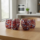 The Talavera Hub hand-blown stemless wine glass with orange, blue, and white swirl pattern. Made from recycled glass.