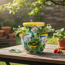 The Talavera Hub handcrafted ceramic strawberry pot with yellow rim, featuring white calla lilies and green foliage, and bumble bee motifs.