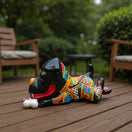 The Talavera Hub handpainted black ceramic dog decor with colorful Talavera patterns and a white bone. Large laying dog sculpture.