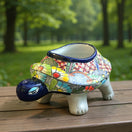 The Talavera Hub hand-painted ceramic turtle planter with colorful floral and geometric designs. Features a dark blue rim and accents.