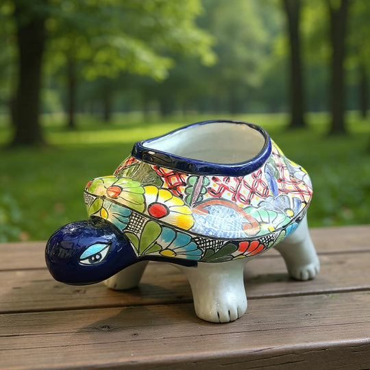 The Talavera Hub hand-painted ceramic turtle planter with colorful floral and geometric designs. Features a dark blue rim and accents.