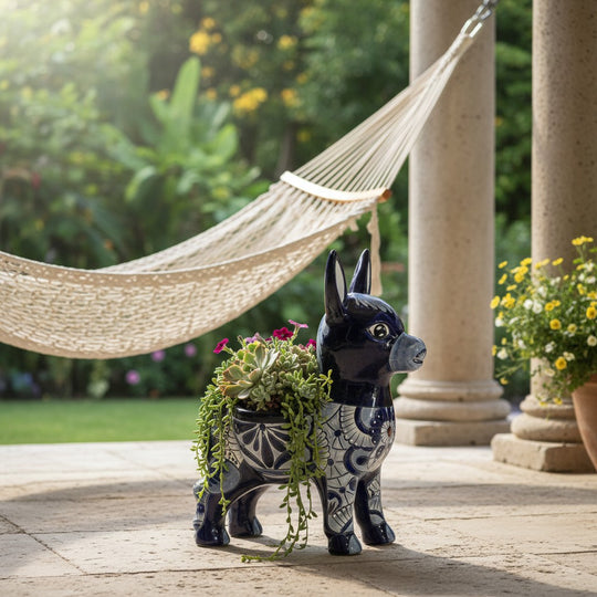 The Talavera Hub large blue and white ceramic donkey planter with hand-painted floral designs. Features two openings for plants.