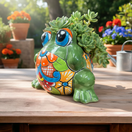 The Talavera Hub medium green Talavera frog planter, hand-painted with vibrant floral patterns in orange, blue, and red.